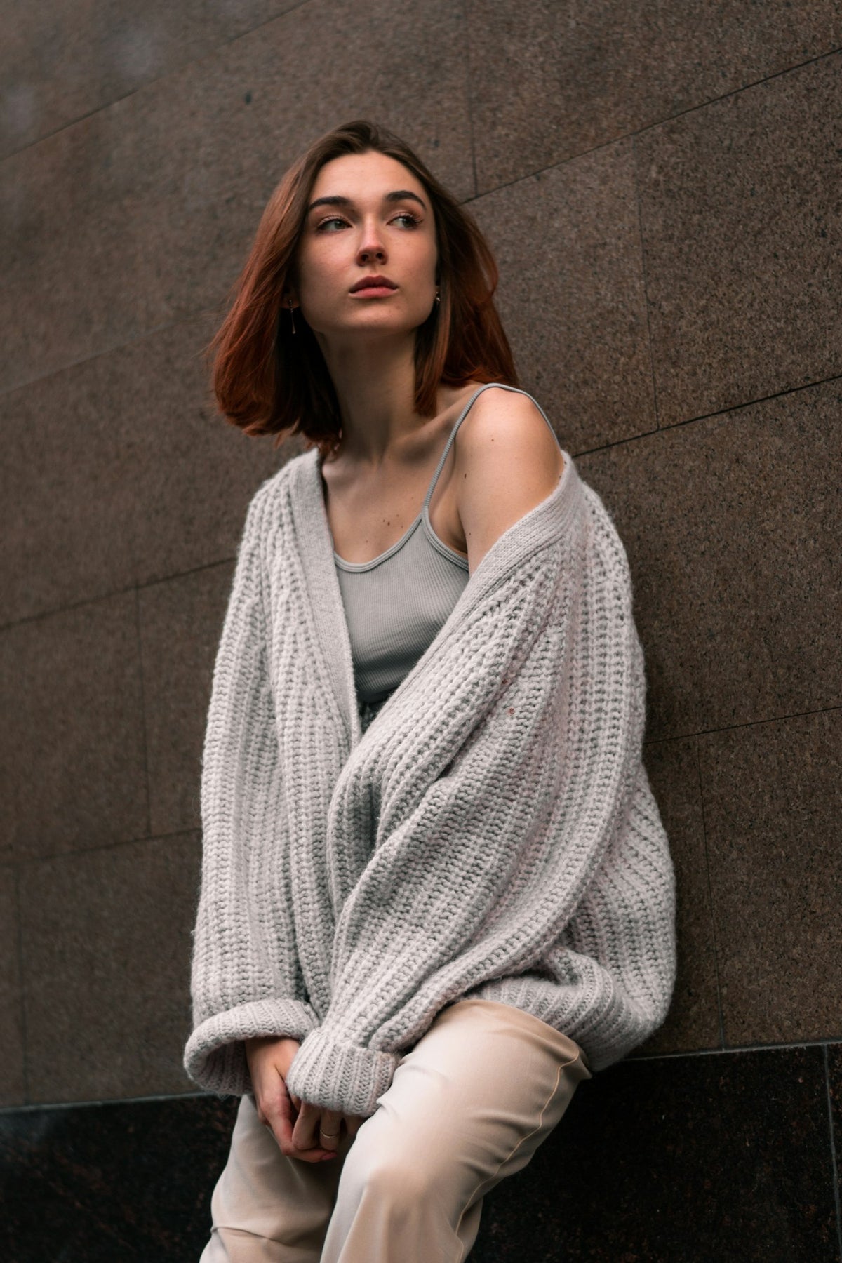 Woman wrapped in a slouchy grey cardigan